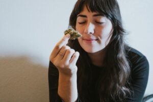 Woman holds up and smells cannabis flower 
